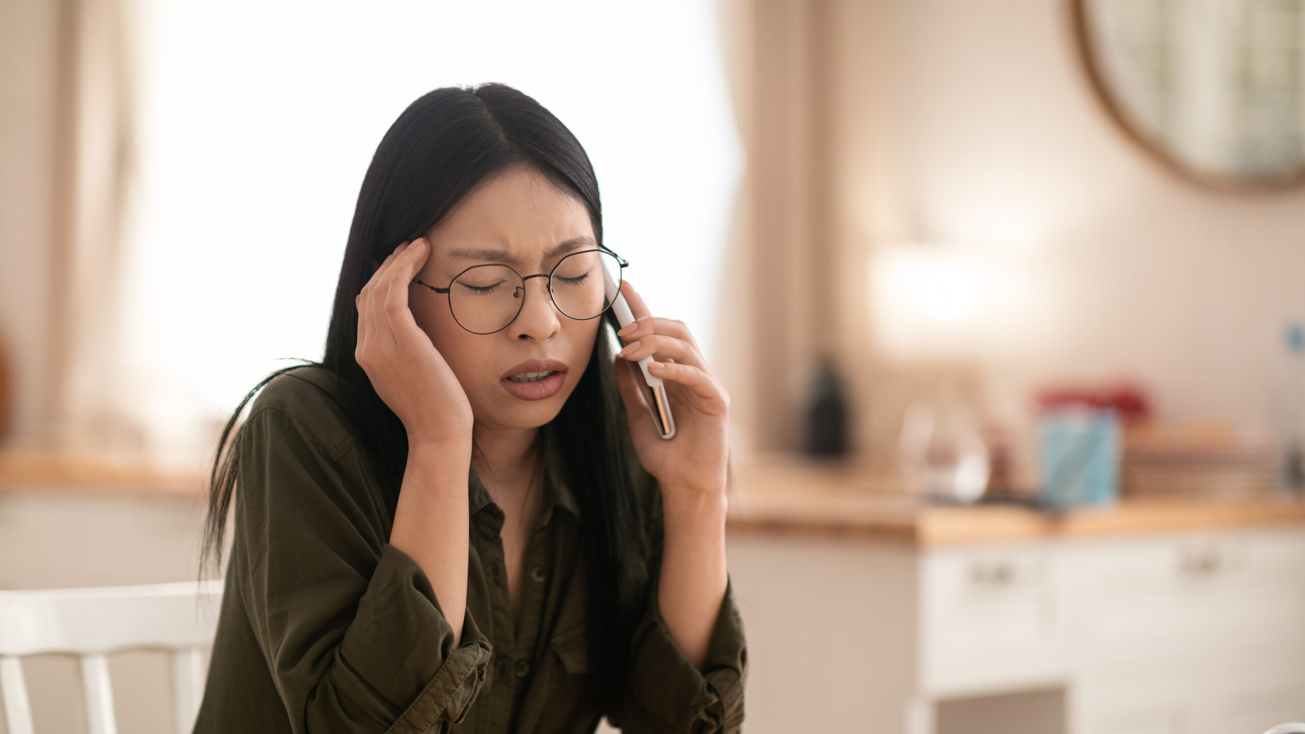 Distressed beautiful asian businesswoman having phone conversation at home, closeup