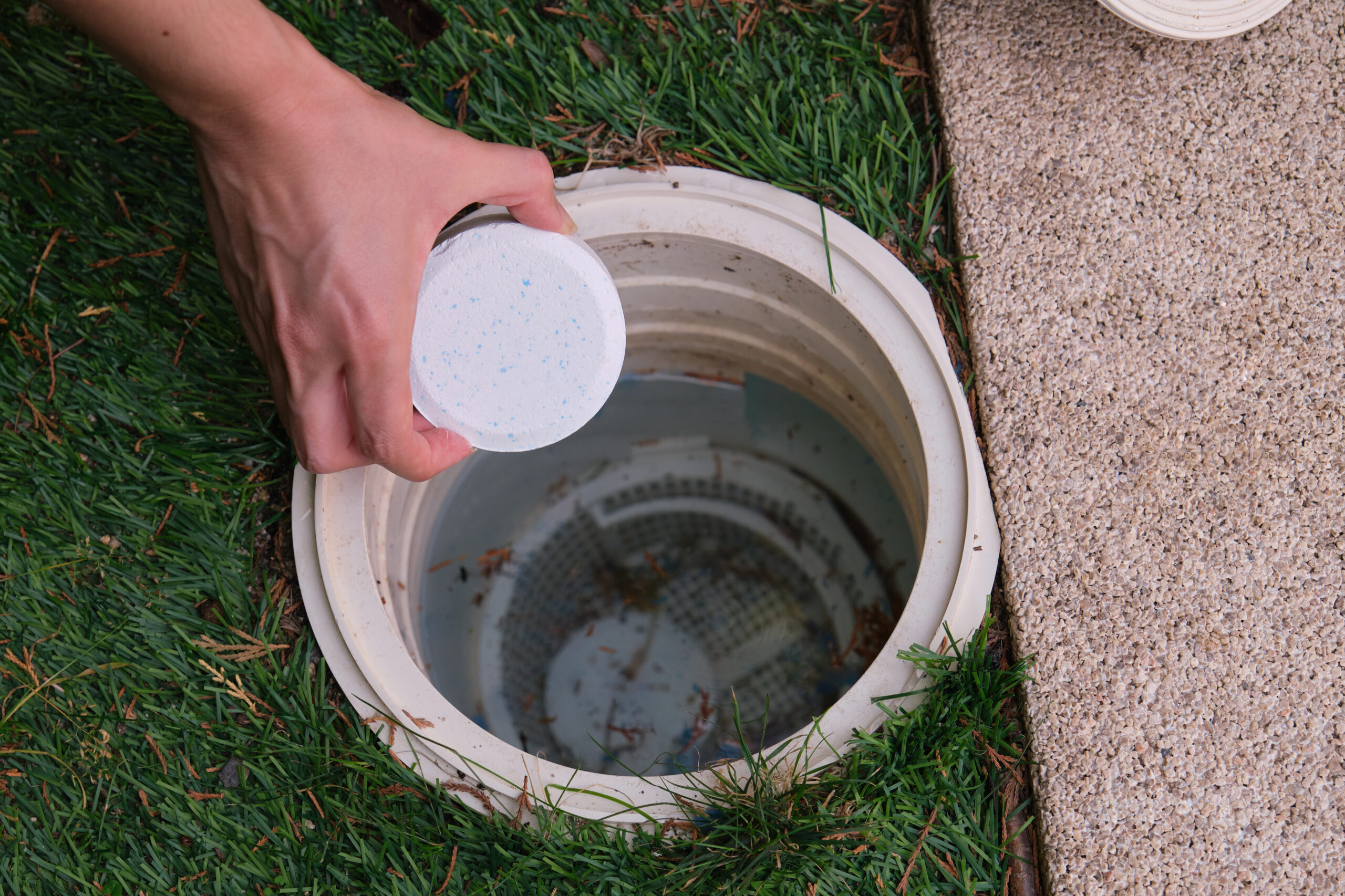 Woman hand putting a chlorine tablet into the pool skimmer