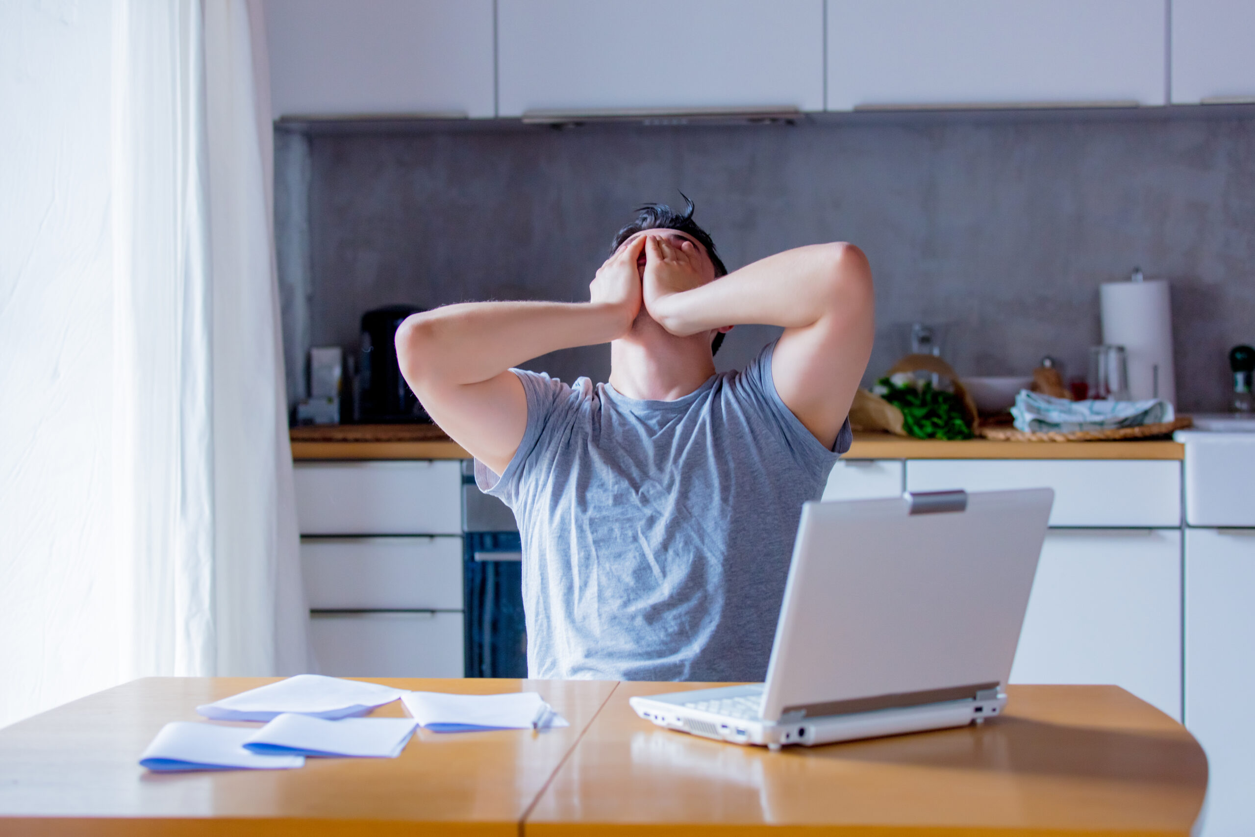 Young man looking for job in Internet while sitting at kitchen